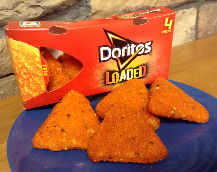 three different triangles shaped like a person's head, on a blue plate with a box of chips