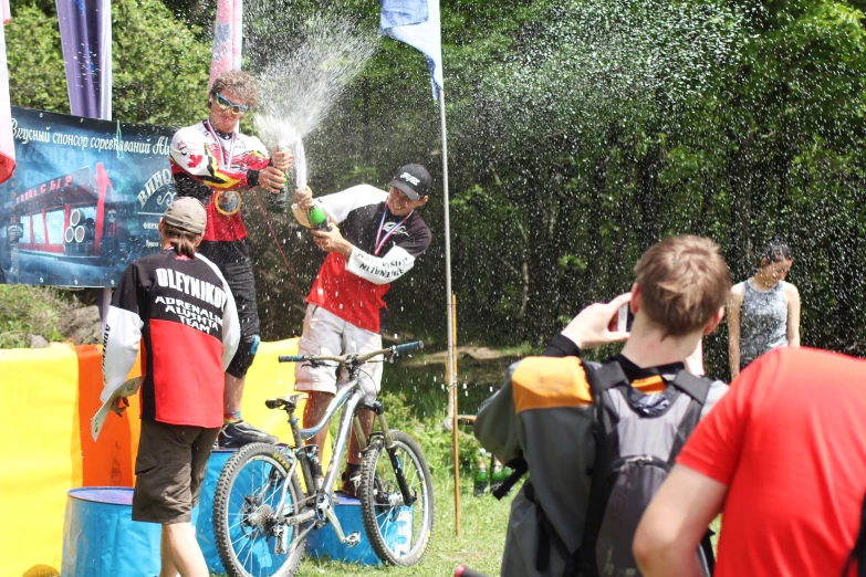 two men on bikes are spraying water onto them