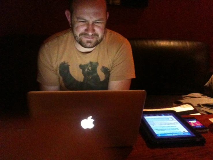 a man sitting at a table working on his apple laptop