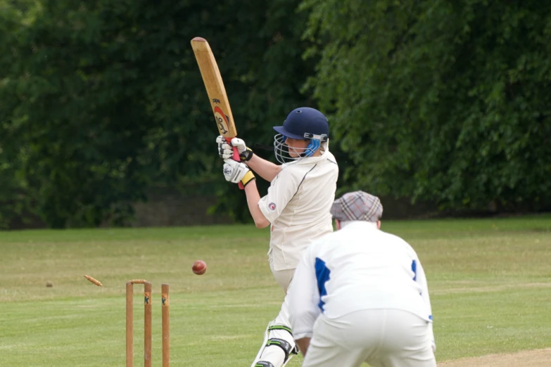 a person in a white uniform holds a bat, ready to swing at a ball