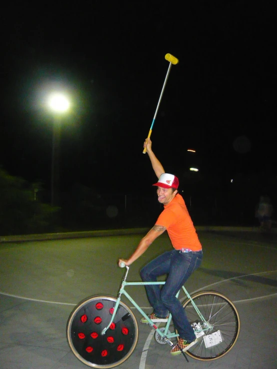 a man riding a bike while holding a broom in his hand