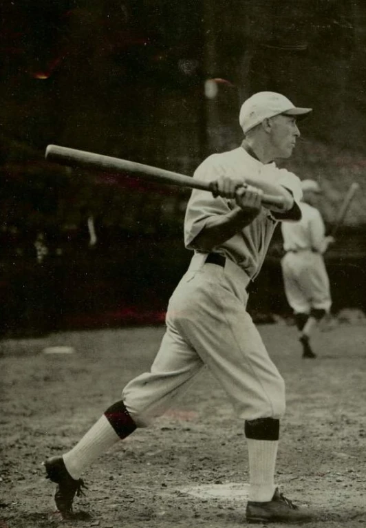 a baseball player holds a bat with one leg