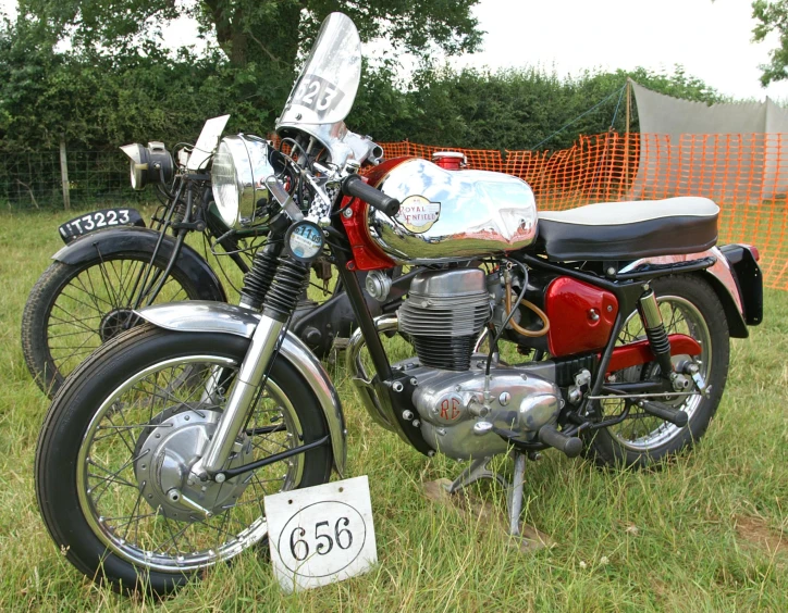 a motorbike parked in the grass next to a fence