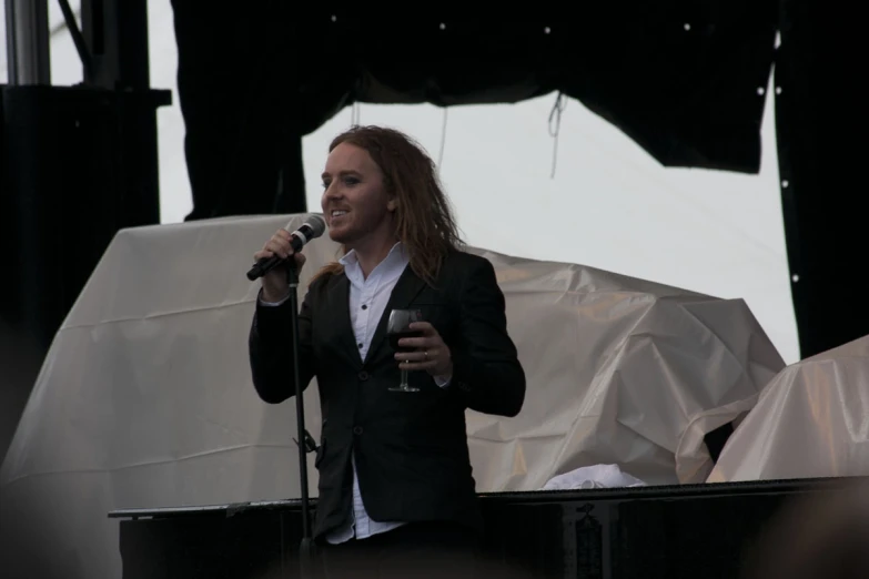 a man is speaking into a microphone in front of white tarps