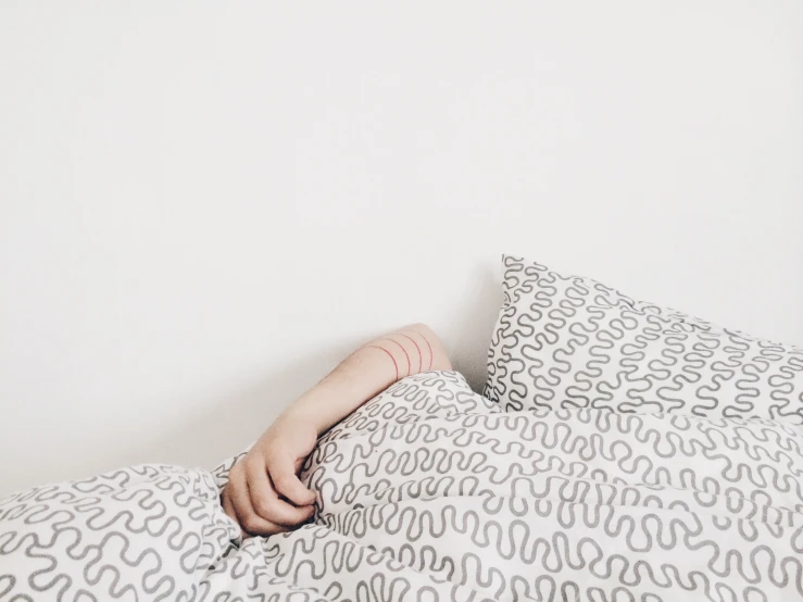 a man laying down in bed with the sheets unmade