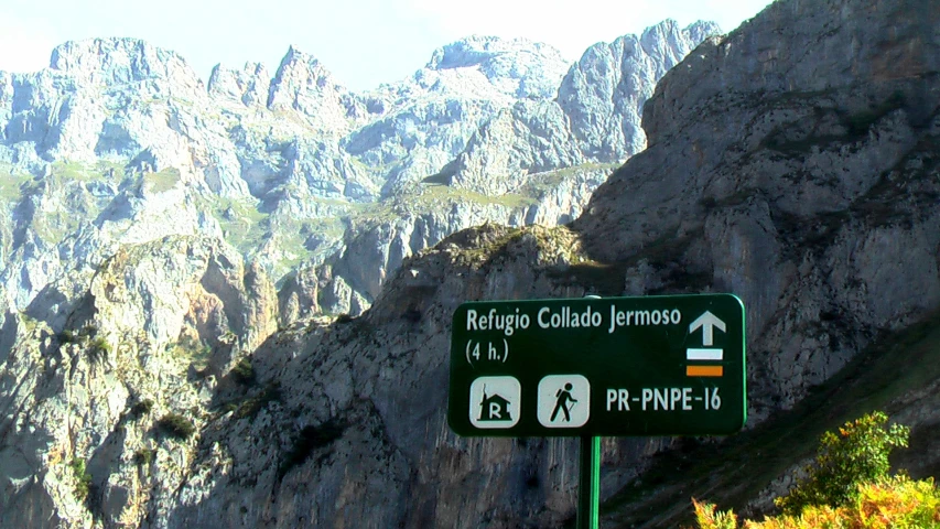 a green road sign on the side of a large mountain