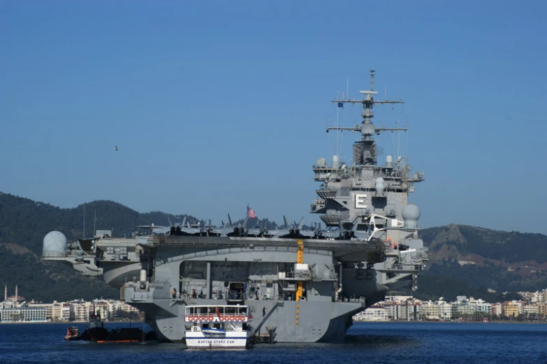 a big battleship sailing along side of a large mountain