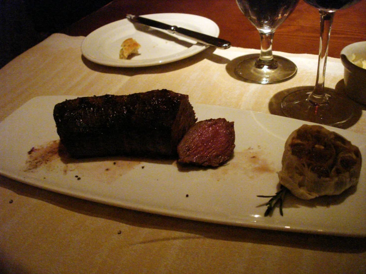 some steak is on a white plate near a glass