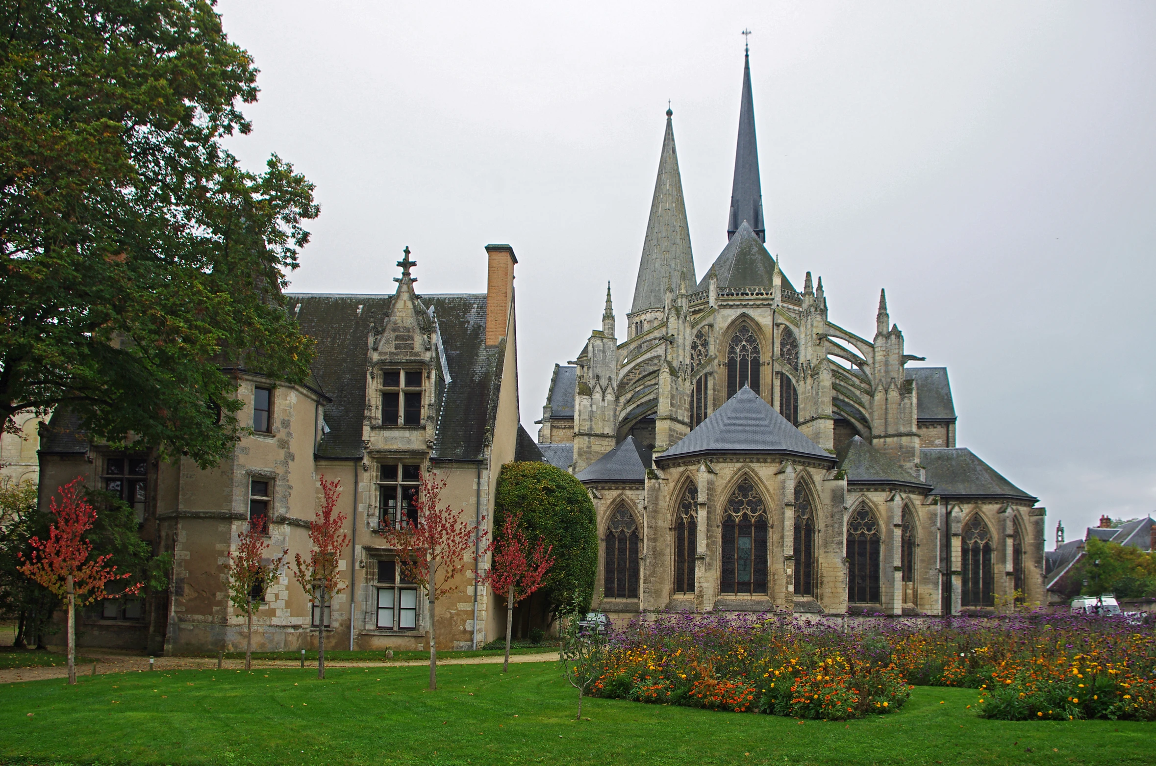 an old church with a clock tower sits next to a garden of flowers