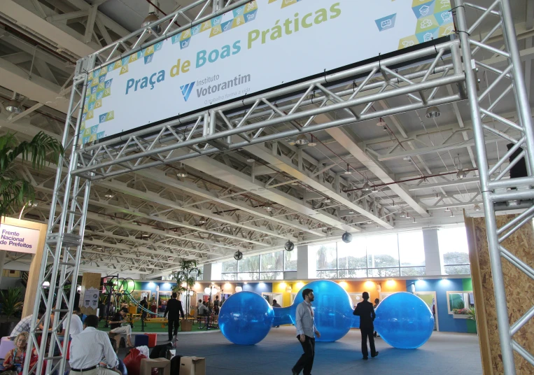 there is a man standing under the stage with several large blue balloons