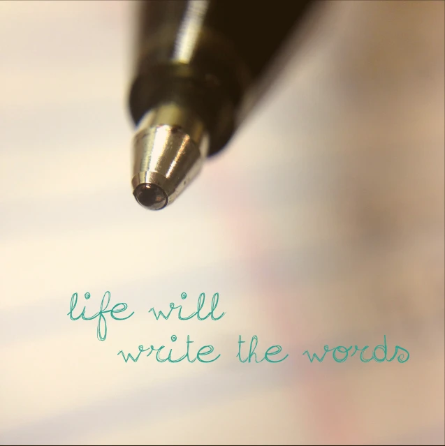 a writing pen is pointed toward a piece of paper that reads life will write the word