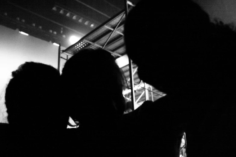 black and white silhouette of a couple's head as they stare at soing on the ground