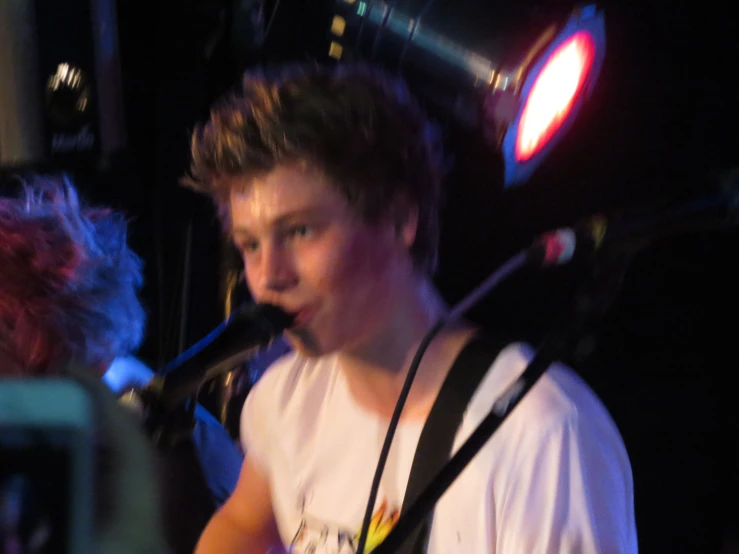 the young man is playing his guitar on stage