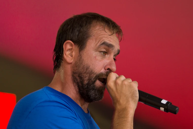 a bearded man is holding his hands together as he sings