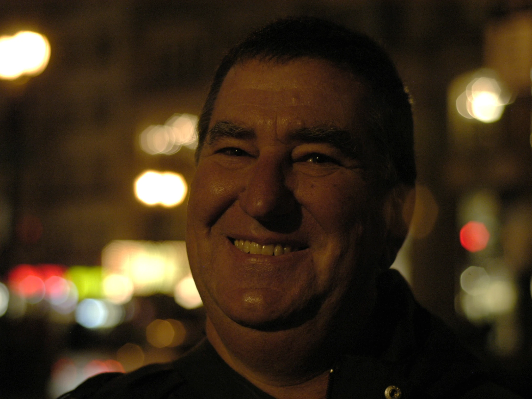 a man smiles while posing for a picture in front of lights