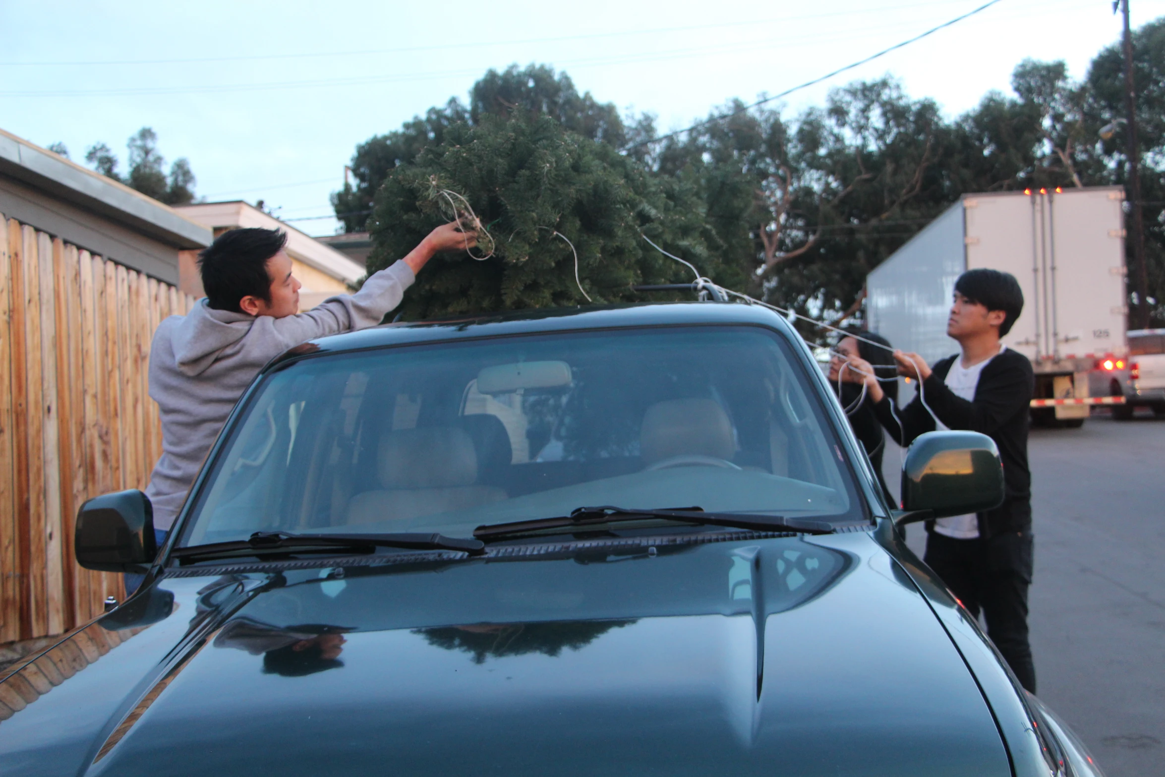 two young men unpacking and cleaning soing off the roof of a car