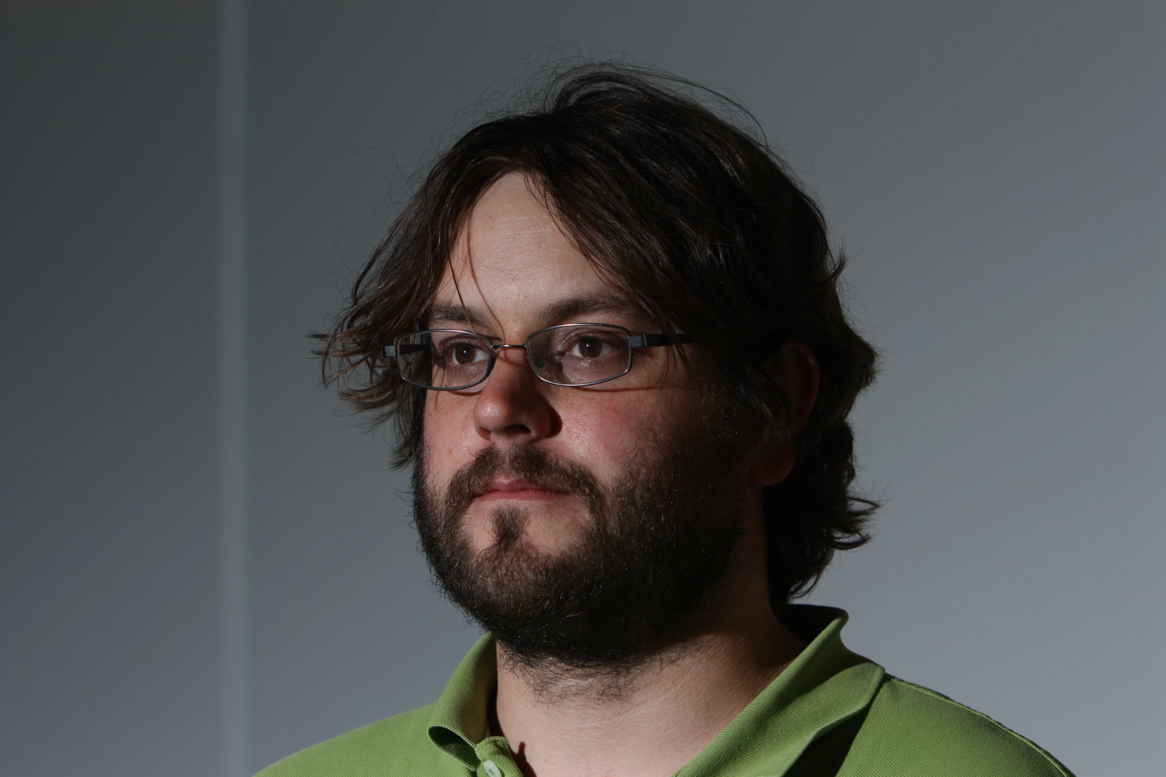 a bearded man wearing glasses and a green shirt