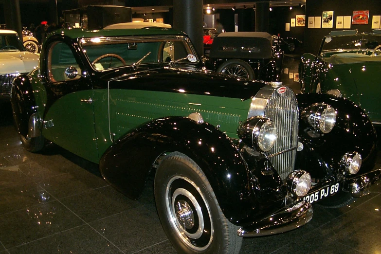 an old time vehicle parked in a museum with other cars