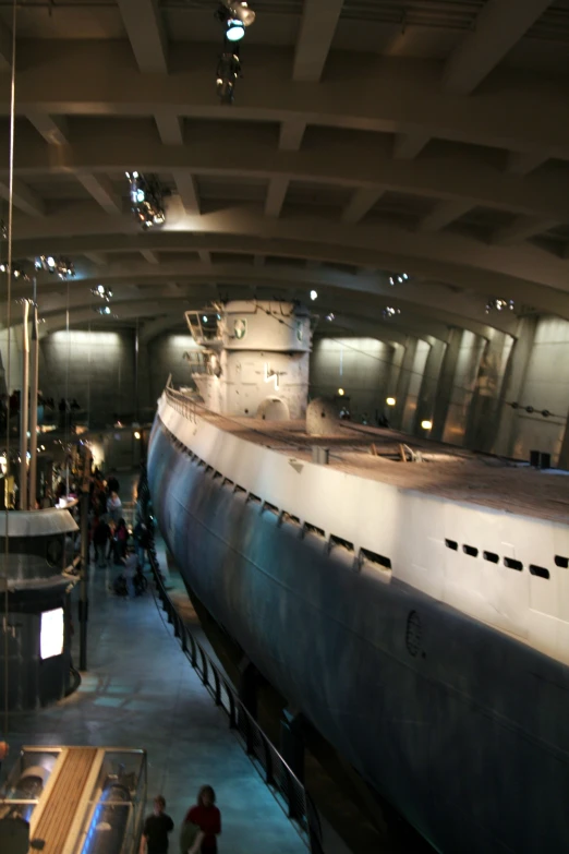 a long boat in a building next to people walking