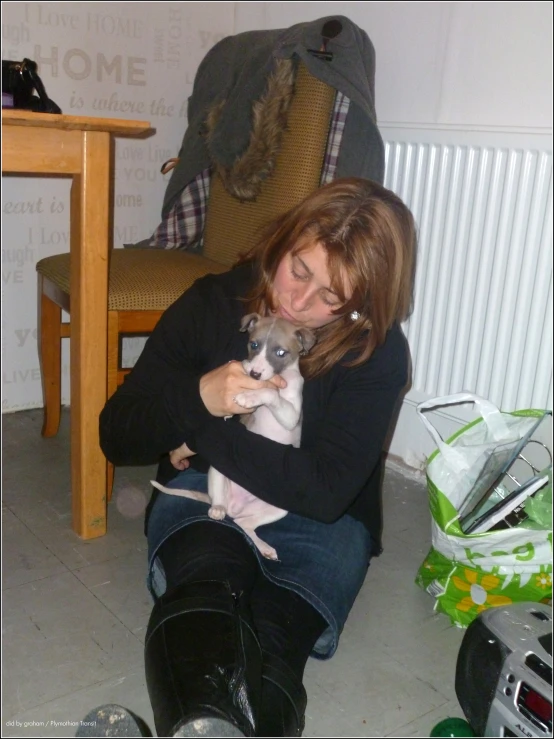 there is a woman holding a small dog and sitting on the floor