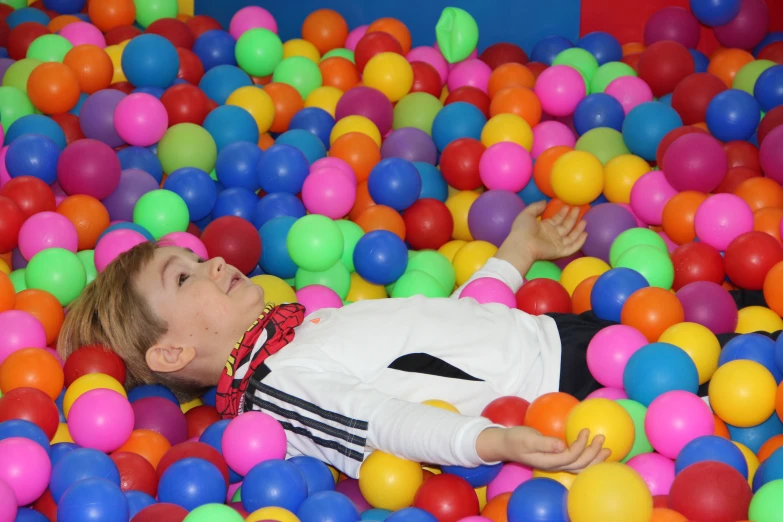 a little girl in ball pit with one hand in it
