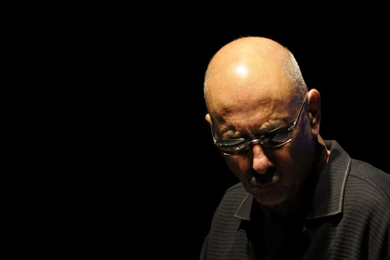 a bald man in glasses is standing