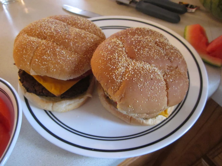 two cheeseburgers on top of white plates with toppings