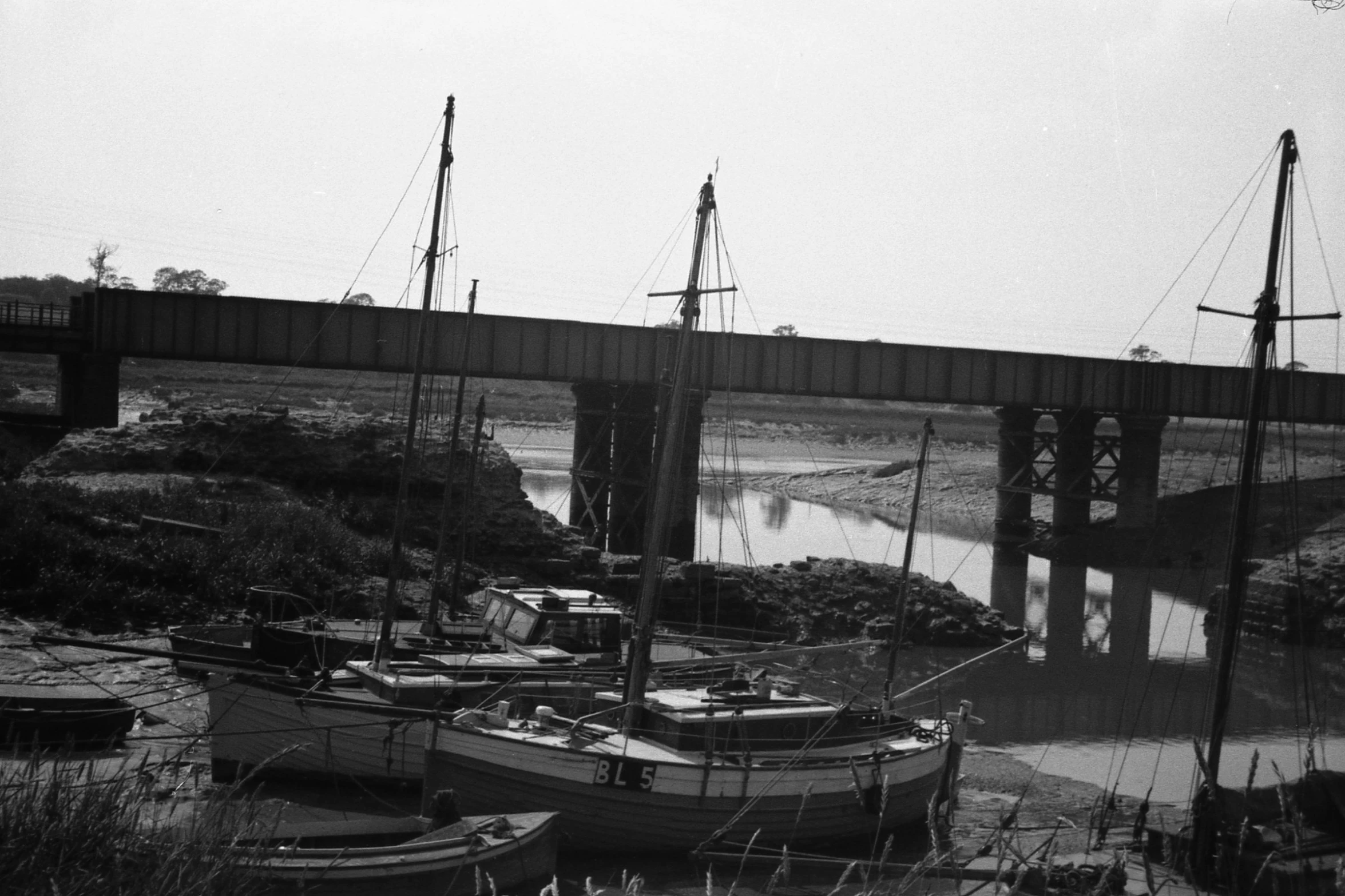 a group of boats are docked by a bridge