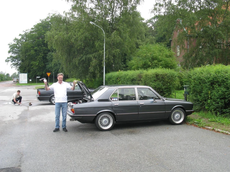 a man stands next to his car in the parking lot