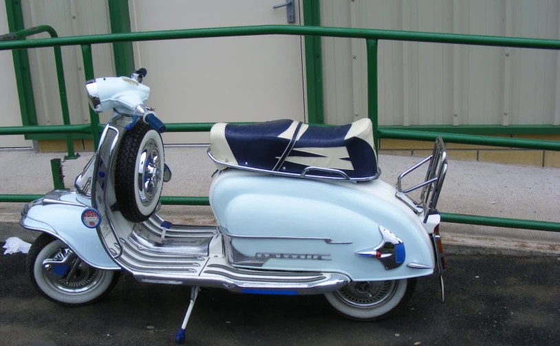 an old model scooter sits parked in a parking lot