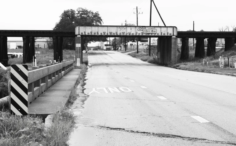 an empty street with only a car and a bridge