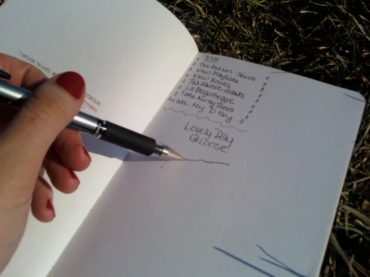 a person's hand writing on a book with a pen