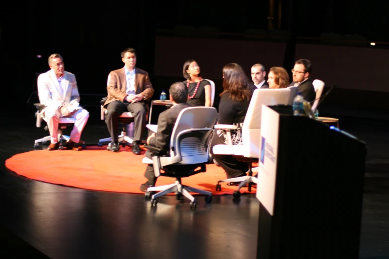 group of people on stage talking to one another