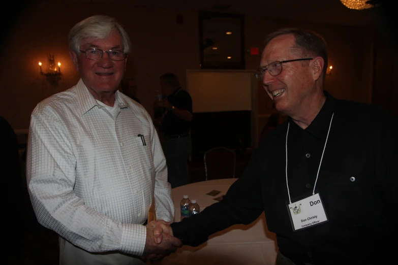 two men are shaking hands while standing at an event