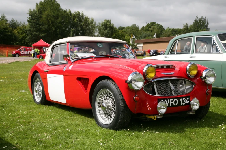 a classic red sports car parked at a festival