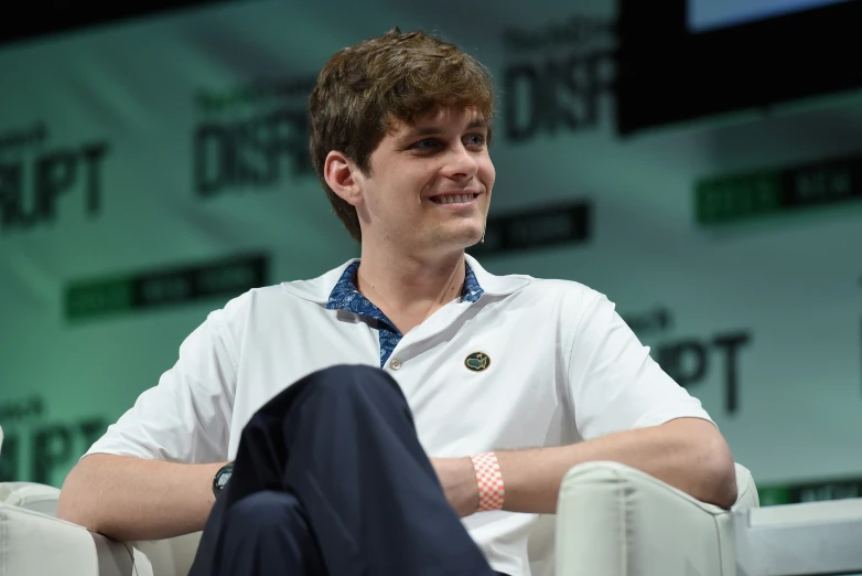 a man in a white shirt and blue pants sits in a chair