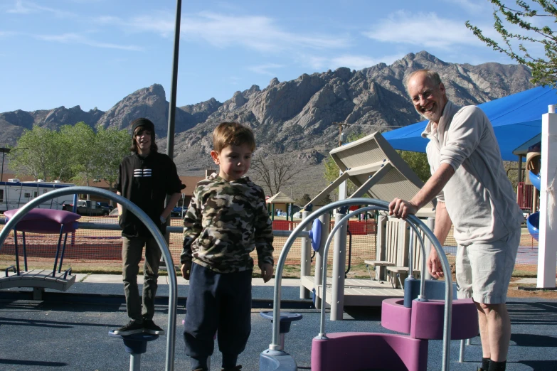 an older man helping children to play on a playground