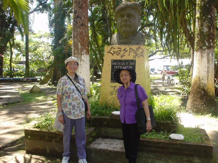 two women posing in front of a stone statue