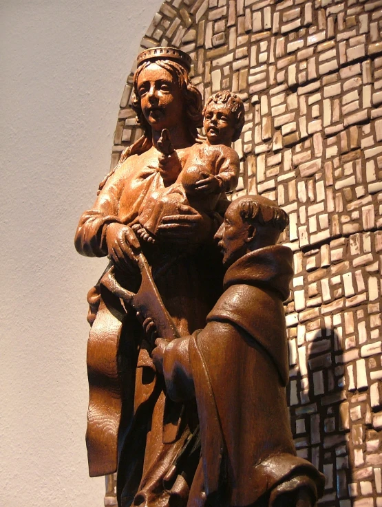 a wooden sculpture of a person holding a baby in his arms