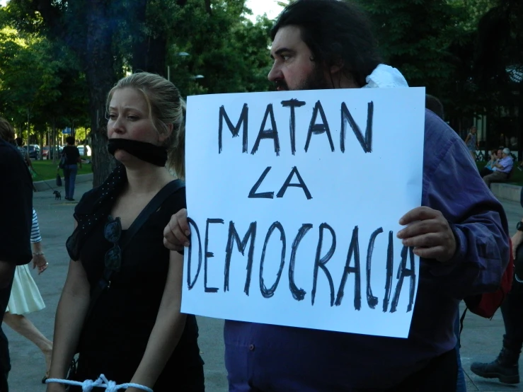a man holding a sign that reads matan za democorach