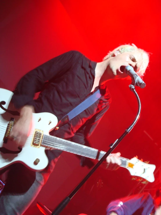 a man on a microphone with a guitar on stage