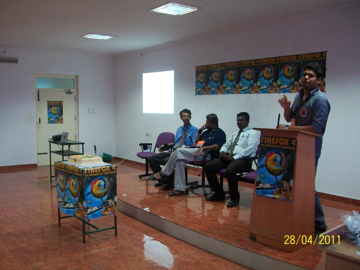 people sitting in chairs at a podium having a discussion