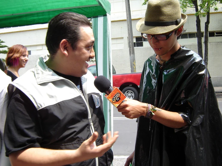 a man is interviewed by a man in a black robe and sunglasses