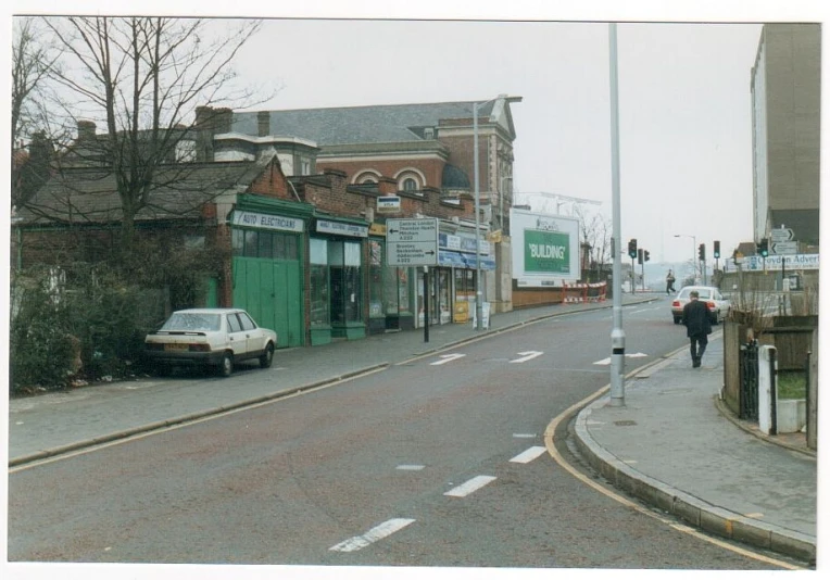 a town street with old buildings and cars parked at the end