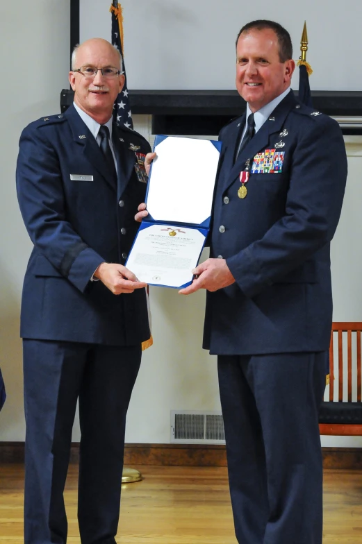 two men holding an award standing next to each other