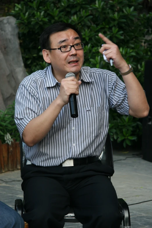 the man is talking into a microphone and is pointing