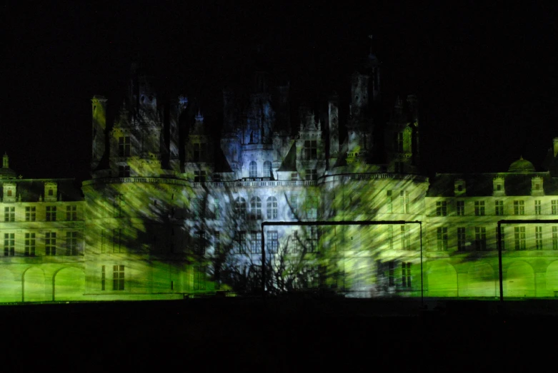 a large castle is seen illuminated in the dark