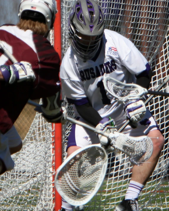 lacrosse player in white uniform preparing to hit ball