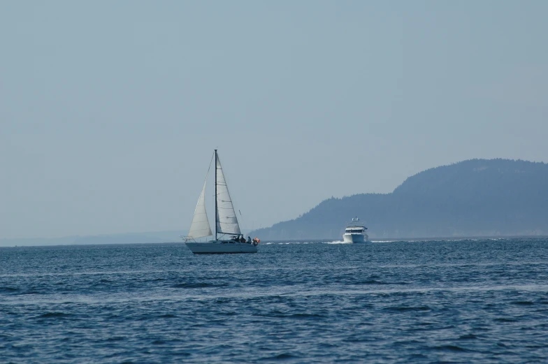 two boats are traveling in the ocean with mountains in the background