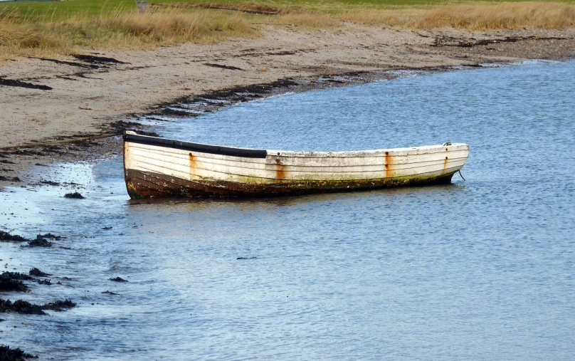 an old boat sitting in shallow water near shore